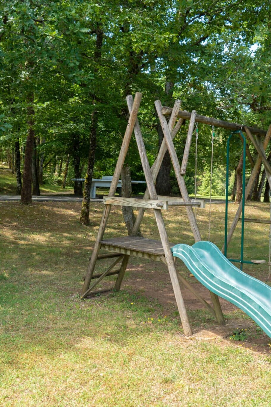 Jeux pour enfants avec toboggan, balançoire et table de ping pong en arrière plan dans le terrain du grand gîte du Clos des Aubiers