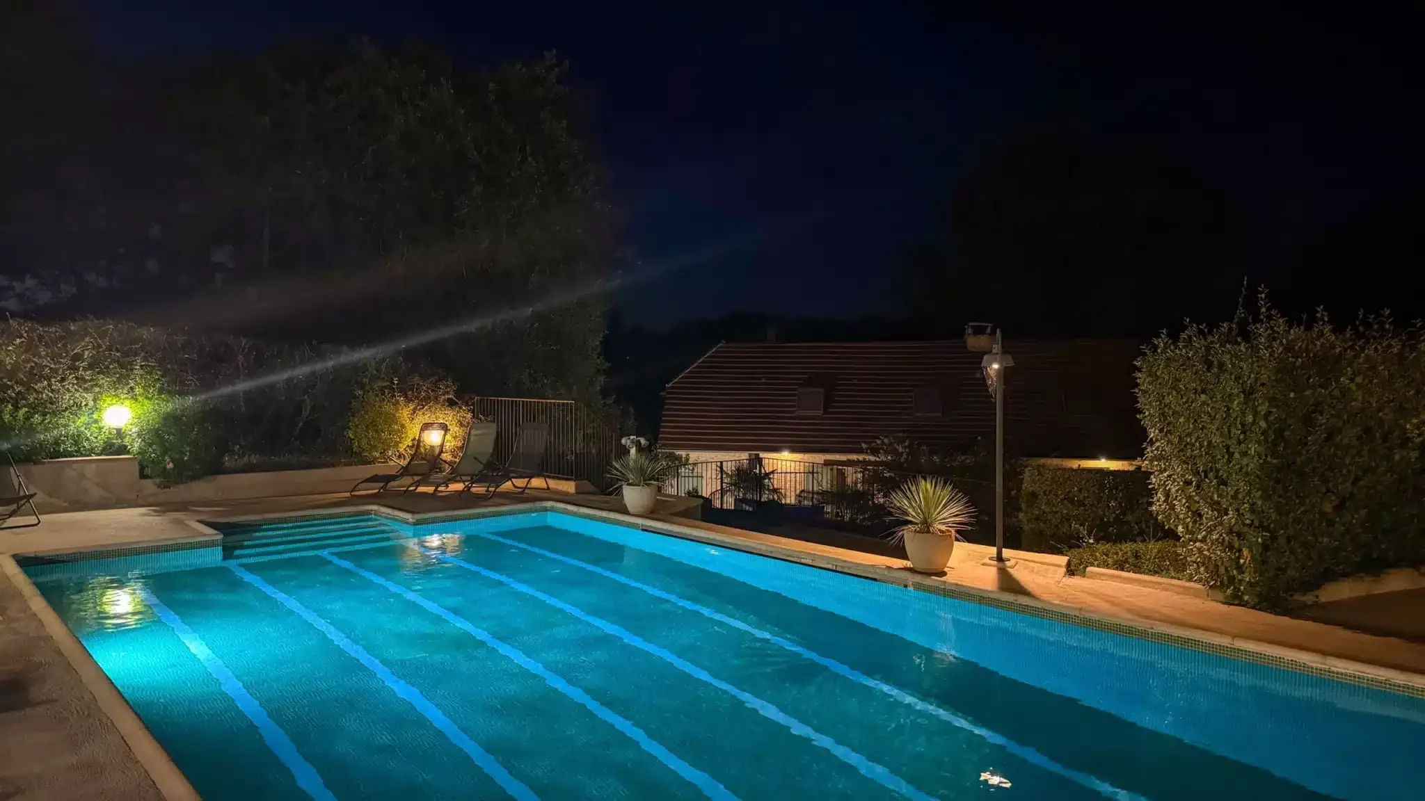 Grande piscine vue de nuit avec éclairage autour et dans la piscine du gîte pour 15 personnes du Clos des Aubiers